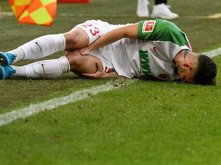 Augsburgs Marco Richter liegt verletzt auf der Seitenlinie. Foto: Stefan Puchner/dpa/Archivbild
