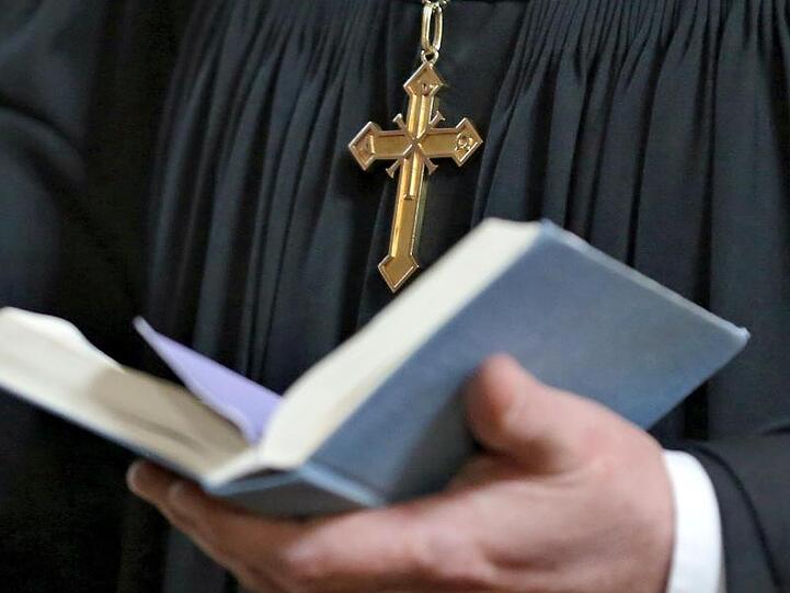 Ein Geistlicher hält eine Bibel in der Hand. Foto: Jan Woitas/Archivbild