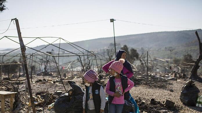 Eine Familie steht im ausgebrannten Flüchtlingslager Moria.