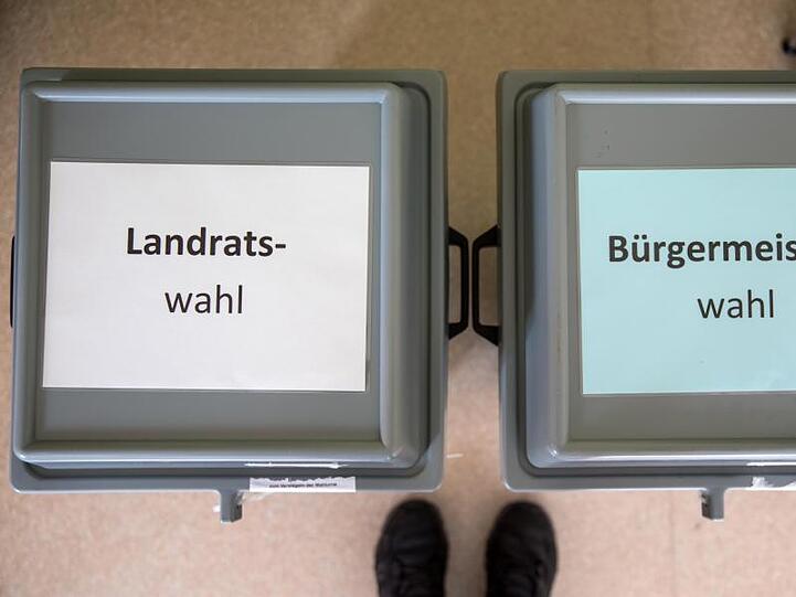 Zettel mit der Aufschrift "Landratswahl" und "Bürgermeisterwahl" liegen auf den Wahlurnen in einem Wahllokal. Foto: arifoto UG/Archiv