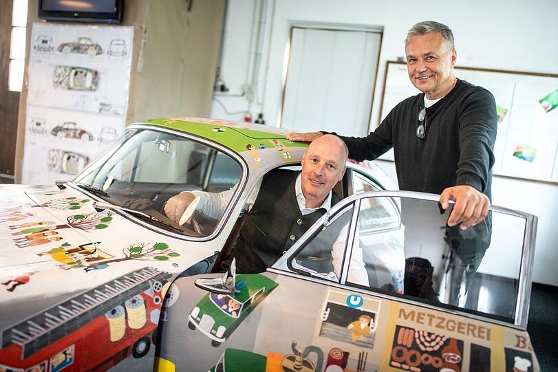 Helmut Freinecker, KFZ-Meister und Oldtimer-Experte (l.), posiert in seinem Porsche mit dem Künstler (r.).