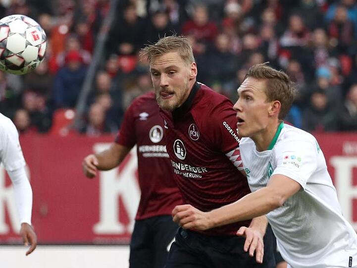 Der Nürnberger Hanno Behrens (M.) kämpft mit dem Bremer Ludwig Augustinsson (r.) um den Ball. Foto: Daniel Karmann