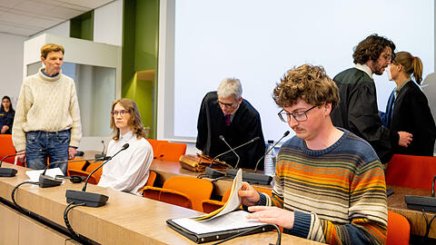 04.05.2023, Bayern, München: Die angeklagten Klimaaktivisten Michael Winter (l-r), Lukas Popp und Simon Lachner sitzen zum Prozessauftakt auf der Anklagebank. Vor dem Amtsgericht München hat am Donnerstag der Prozess gegen Klimaaktivisten, die sich im vergangenen August am Rahmen eines Rubens-Gemäldes in der Alten Pinakothek in München festgeklebt haben, begonnen. Foto: Lennart Preiss/dpa +++ dpa-Bildfunk +++