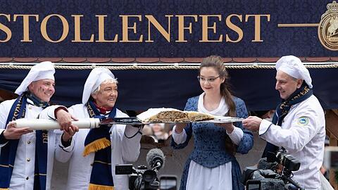 Das Dresdner Stollenmädchen und die Bäcker der Schutzgemeinschaft Dresdner Stollen präsentieren das erste Stück vom Riesenstollen.