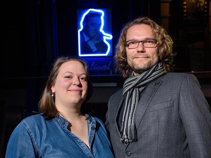 Festivalleiterin Svenja Böttger und Programmleiter Oliver Baumgarten vor einem Neon-Bild von Max Ophüls.