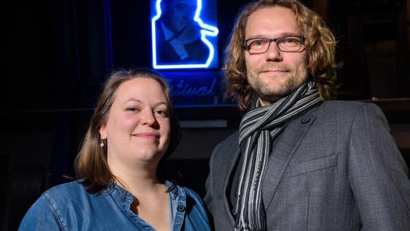Festivalleiterin Svenja Böttger und Programmleiter Oliver Baumgarten vor einem Neon-Bild von Max Ophüls.