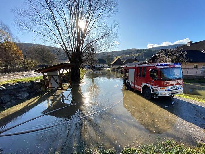 Ein Feuerwehrfahrzeug steht auf einer überfluteten Straße in Kärnten.