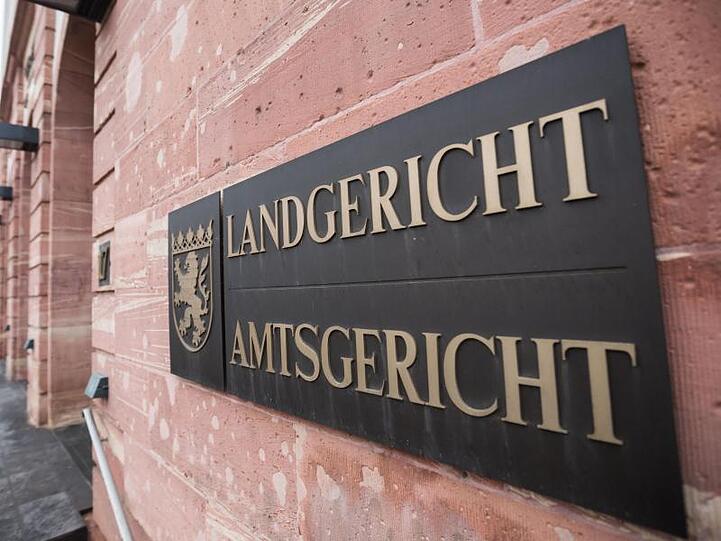 Ein Schild mit dem Landeswappen ist am Gebäude des Land- und Amtsgerichtes befestigt.