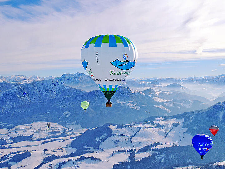 Bunte Heißluftballone am Himmel über der Region Kaiserwinkl