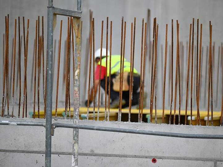 Ein Handwerker arbeitet auf einer Baustelle an Betonstahlträgern.