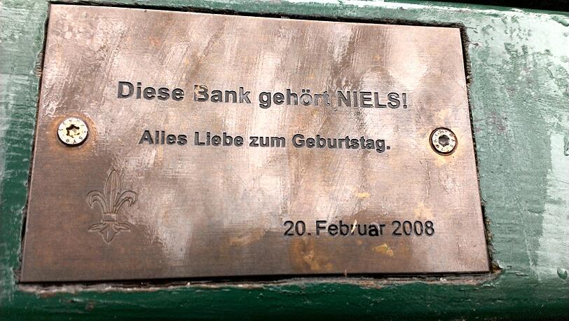 Im Englischen Garten und Nymphenburger Schlosspark haben Münchner tausende Plaketten mit Widmungen auf Parkbänken angebracht.