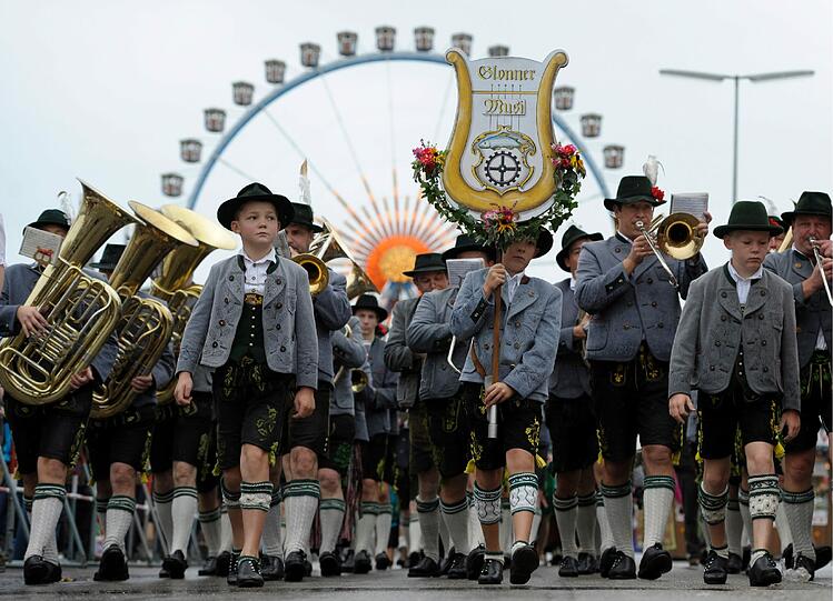 Eine Musikgruppe zieht auf der Theresienwiese vor dem Riesenrad entlang.