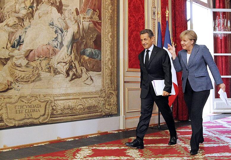 Frankreichs Staatspräsident Nicholas Sarkozy und Bundeskanzlerin Angela Merkel sind am Dienstag auf dem Weg zur Pressekonferenz im Elysée-Palast. Sie präsentieren ihren Lösungsansatz zur Euro-Stabilisierung in der Schuldenkrise.