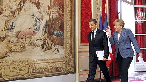 Frankreichs Staatspräsident Nicholas Sarkozy und Bundeskanzlerin Angela Merkel sind am Dienstag auf dem Weg zur Pressekonferenz im Elysée-Palast. Sie präsentieren ihren Lösungsansatz zur Euro-Stabilisierung in der Schuldenkrise.
