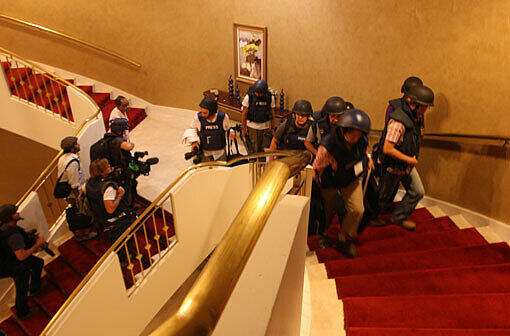 Mit Helmen und kugelsicheren Westen bekleidete ausländische Journalisten steigen am Dienstag eine Treppe im Rixos-Hotel von Tripolis empor. Anhänger des libyschen Diktators hatten 35 ausländische Journalisten in dem Nobelhotel festgehalten.