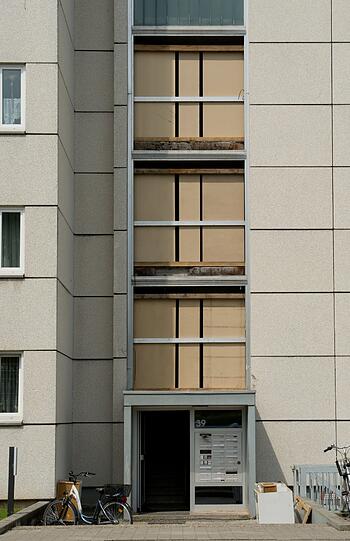 Die durch eine Explosion zerstörte Fassade des Treppenhauses ist am Montag in Garching bei München provisorisch mit Holz verkleidet. Aus unbekannten Gründen ist die Glasfassade eines Treppenhauses am 24.05.2014 geborsten. Ein Mann wurde dabei verletzt.