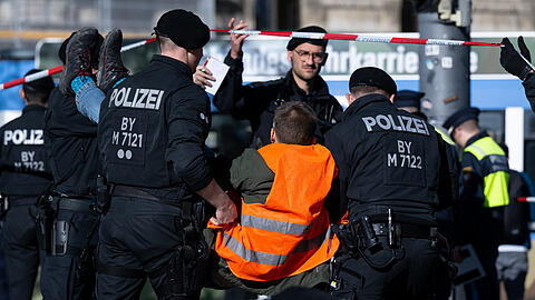 Polizisten tragen einen Klimaaktivisten weg, der sich zuvor am Karlsplatz in der Innenstadt auf die Straße geklebt hat.