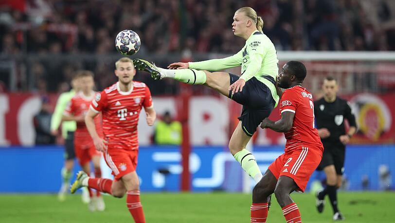 Manchester Citys Erling Haaland und Münchens Dayot Upamecano (r) kämpfen um den Ball.