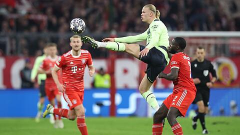 Manchester Citys Erling Haaland und Münchens Dayot Upamecano (r) kämpfen um den Ball.
