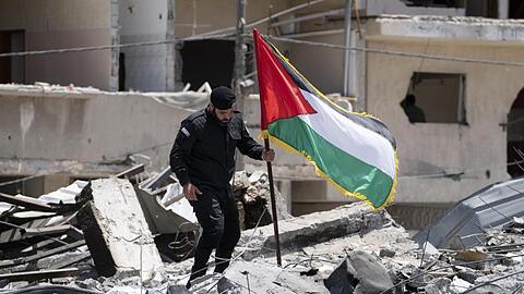 Ein Polizist der Hamas entfernt eine palästinensische Fahne von einem Trümmerhaufen eines Bahnhofsgebäudes, das bei Luftangriffen zerstört worden war.