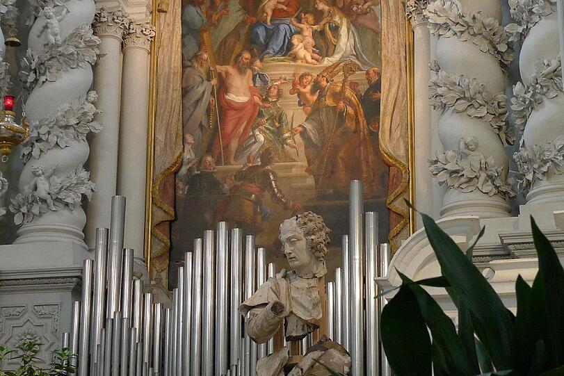 Lukasfigur vor der Orgel und Wandbild.