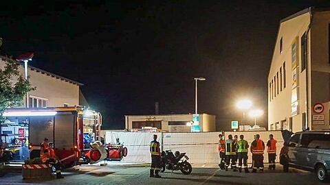 Feuerwehrleute stehen in der Nähe des Tatorts vor der Zufahrt zu einem Supermarkt. Foto: Markus Zechbauer/Zema Medien/dpa