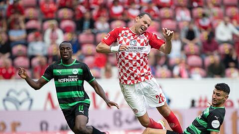 Fürths Dickson Abiama (l-r), der Mainzer Ádám Szalai und Fürths Maximilian Bauer kämpfen um den Ball.