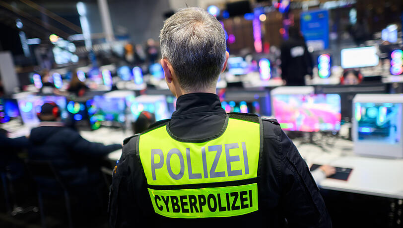 Ein Polizist von der zentralen Ansprechstelle Cybercrime im Landeskriminalamt Niedersachsen steht mit einer Weste mit Aufschrift "Cyberpolizei" bei der Messe "Gamevasion" in der Messe Hannover. Ein Polizist von der zentralen Ansprechstelle Cybercrime im Landeskriminalamt Niedersachsen steht mit einer Weste mit Aufschrift "Cyberpolizei" bei der Messe "Gamevasion" in der Messe Hannover.