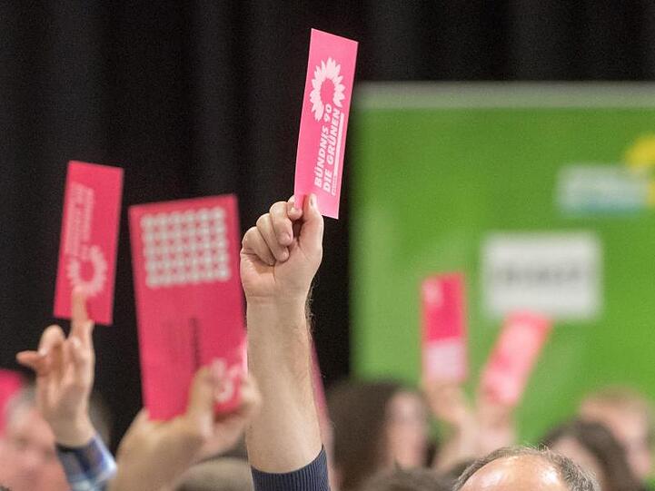 Delegierte halten beim Landesparteitag der bayerischen Grünen ihre Wahlzettel nach oben. Foto: Armin Weigel/Archiv