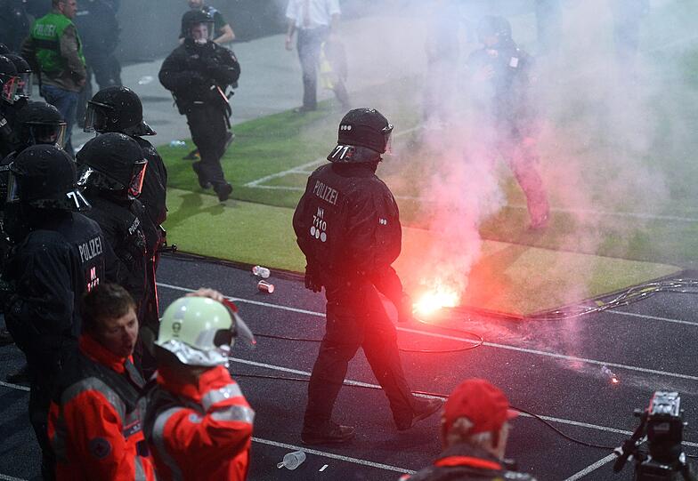 Braunschweiger Fans stehen Polizisten und Ordnern nach dem Abpfiff auf dem Platz gegenüber.