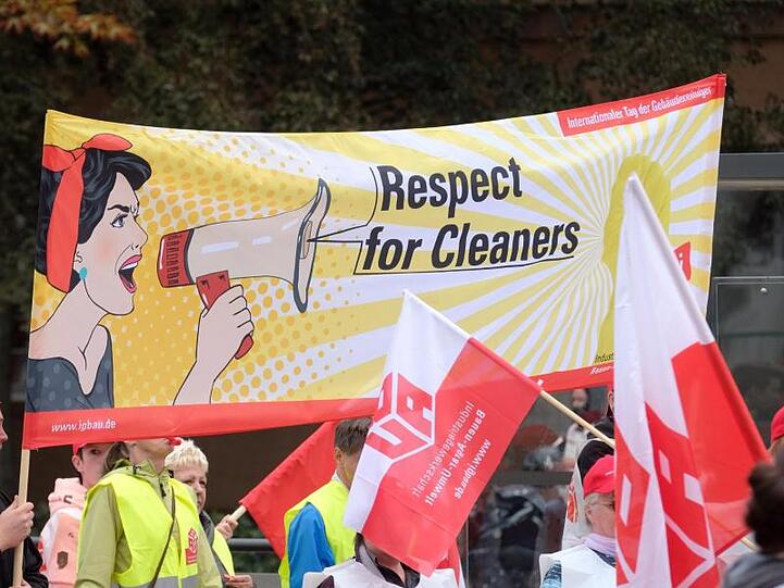Fenster- und Fassadenreiniger, Putzkräfte sowie Reiniger von Industriemaschinen während einer Demonstration.