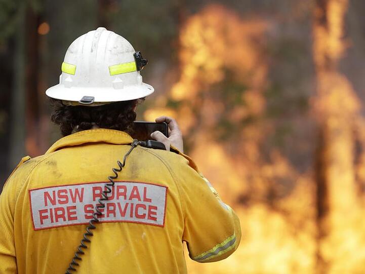 Ein Feuerwehrmann fotografiert mit seinem Smartphone eines der Buschfeuer bei Tomerong. Rund 2.300 Feuerwehrleute sind im Bundesstaat New South Wales bei etwa 110 Buschbrände im Einsatz.