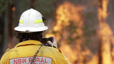 Ein Feuerwehrmann fotografiert mit seinem Smartphone eines der Buschfeuer bei Tomerong. Rund 2.300 Feuerwehrleute sind im Bundesstaat New South Wales bei etwa 110 Buschbrände im Einsatz.