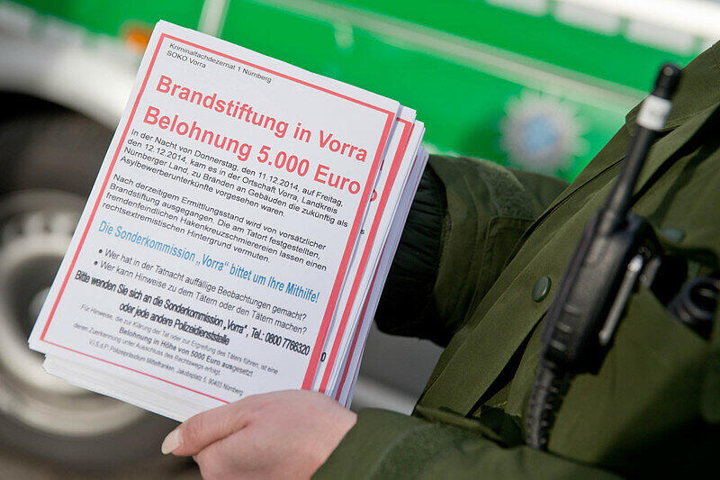 Eine Polizistin hält am 13.12.2014 in Vorra (Bayern) Fahndungszettel zum Brandanschlag in der Gemeinde in den Händen. Die Polizei sucht fieberhaft nach den Verbrechern.