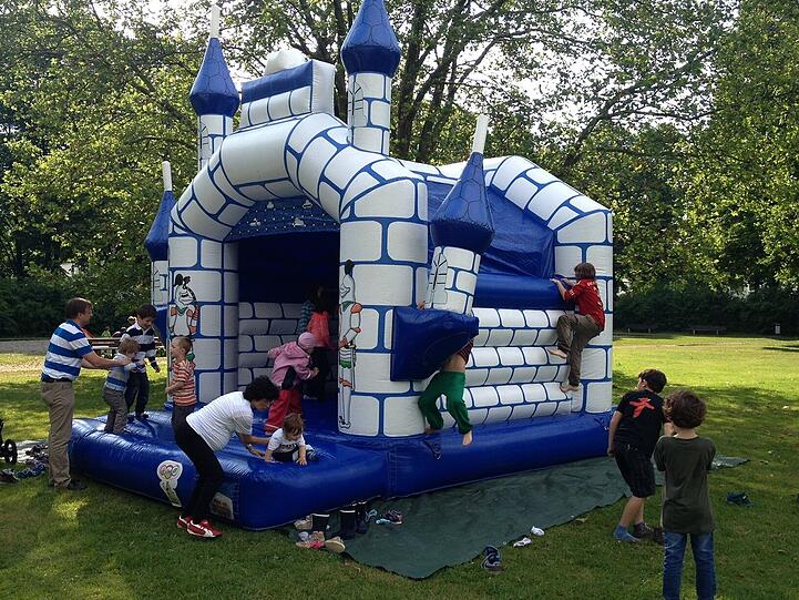 Die Kinder toben in einer weißblauen Hüpfburg.