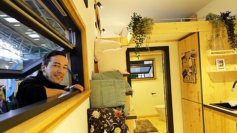 Markus Kastenberger schaut durch das Fenster des Tiny House des Herstellers "Winzig Wohnen" in der Messehalle B5. Der Holzexperte hat es selbst mitgebaut. Etwa 100.000 Euro würde das grundsätzlich mobile, 27 Quadratmeter große Häuschen samt Inneneinrichtung in etwa kosten. Es stecken rund 1.000 Arbeitsstunden drin.