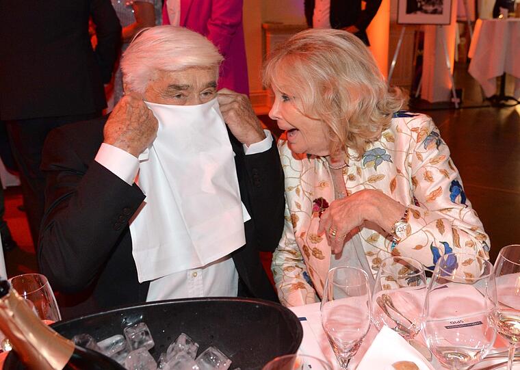 Bisserl Spaß muss sein: Mario Adorf macht Faxen mit der Serviette für die Fotografen - auch Ehefrau Monique amüsiert's. Der Schauspieler hat sich zu elegant für den Abend angezogen und gleich nach der Ankunft seine Krawatte abgenommen.
