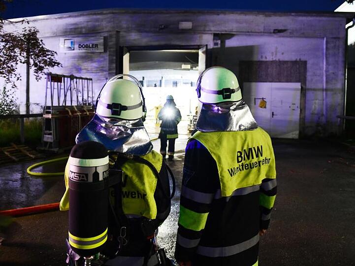 Einsatzkräfte der BMW-Werksfeuerwehr stehen vor einer Halle auf dem Werksgelände. Foto: Tobias Hase