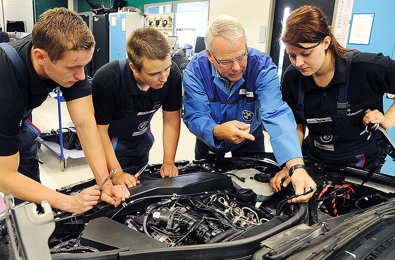 Kfz-Mechatroniker-Lehrlinge arbeiten an einem BMW. Die Zufriedenheit in diesem Ausbildungsberuf ist sehr hoch.