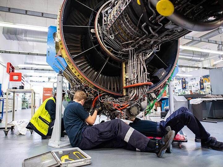 Drei Männer arbeiten in einer Werkstatt von Lufthansa Technik am Triebwerk eines Flugzeuges (Archiv).