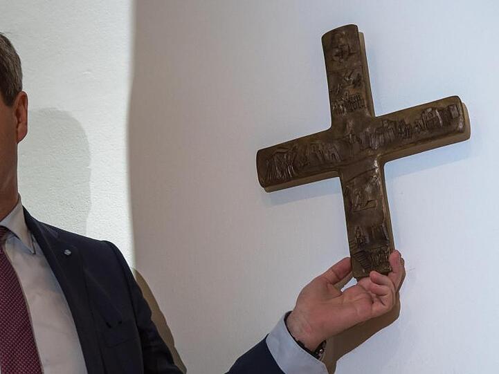 Markus Söder, Bayerischer Ministerpräsident (CSU), hängt ein Kreuz in der bayerischen Staatskanzlei auf. Foto: Peter Kneffel/Archiv