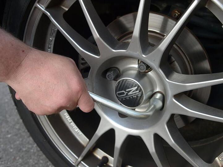 Ein Mann löst eine Radmutter an einer Autofelge. Foto: picture alliance/dpa/Archivbild/Illustration