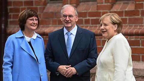 Reiner Haseloff (CDU), Ministerpräsident von Sachsen-Anhalt, und seine Frau Gabriele (l) begrüßen Bundeskanzlerin Angela Merkel (CDU) vor Beginn eines ökumenischen Gottesdienstes an der Pauluskirche in Halle/Saale.
