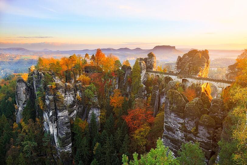 Hier trifft Herbstzauber auf faszinierende Felsformationen: Im Elbsteingebirge in Sachsen wechseln sich satte Rot-, Orange- und Gelbtöne mit dem Grau der bizarren Schrammsteine ab - ein einzigartiger Anblick. Von Aussichtspunkten wie der Bastei eröffnet sich ein Panorama, bei dem die farbenprächtigen Wälder wie ein Teppich zwischen den Felsnadeln und dem Elbtal liegen. Hier trifft Herbstzauber auf faszinierende Felsformationen: Im Elbsteingebirge in Sachsen wechseln sich satte Rot-, Orange- und Gelbtöne mit dem Grau der bizarren Schrammsteine ab - ein einzigartiger Anblick. Von Aussichtspunkten wie der Bastei eröffnet sich ein Panorama, bei dem die farbenprächtigen Wälder wie ein Teppich zwischen den Felsnadeln und dem Elbtal liegen.