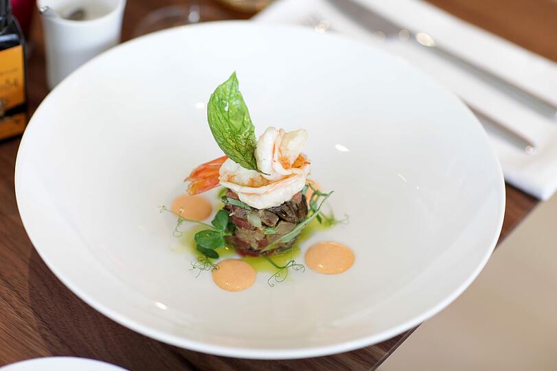 Salzwasser-Scampi mit Auberginen-Caponata, Rauchpaprika-Aioli und Basilikumöl: Der Scampi schmeckt, als wäre er direkt vom Meer auf den Teller gesprungen um dort eine harmonische Bindung mit dem Auberginen-Caponata, einer Art sizilianisches Ratatouille mit Kapern, einzugehen. Dazu die Aioli, das Basilikumöl &ndash; ein Gedicht, andächtig begleitet vom Torfel &bdquo;San Martino della Bataglia&ldquo; aus der Lombardei, mit angenehm fülligem Körper.