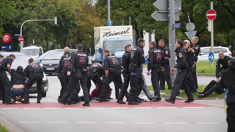 Aktivisten wollen die Lerchenauer Straße blockieren. Polizisten greifen sofort ein und tragen sie weg.