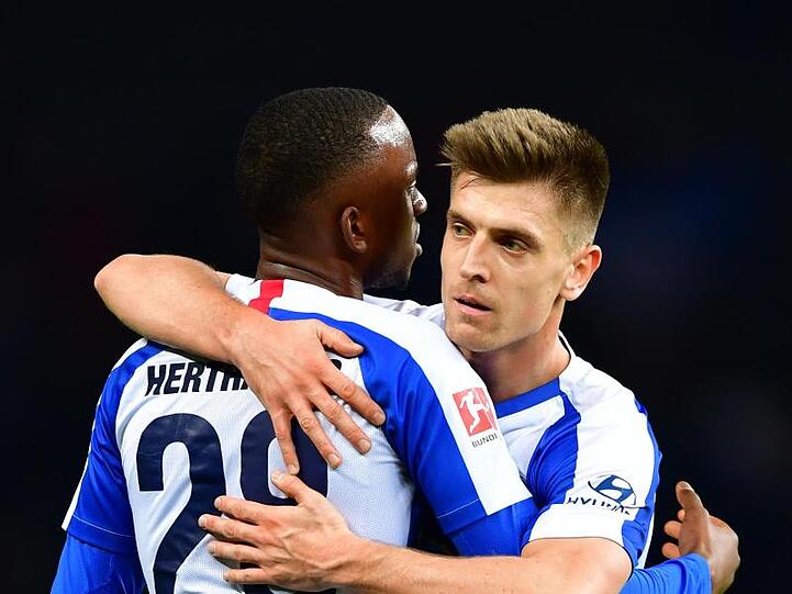 Neuzugang Krzysztof Piatek (r) und Dodi Lukebakio von Hertha umarmen sich nach Spielende.