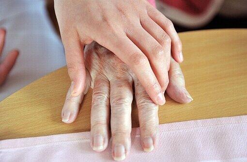 Pflege in Deutschland: Eine Hand einer Krankenpflegeschülerin liegt in der Seniorenresidenz Acabelle de Fleur in Karlsruhe (Baden-Württemberg) auf einer Hand einer Seniorin.