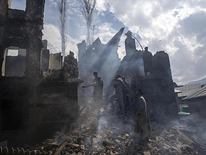 Kaschmirische Männer demontieren im Dorf Tral, südlich von Srinagar im indisch kontrollierten Kaschmir, einen Teil eines bei einem Schusswechsel zerstörten Hauses.