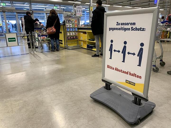Ein Hinweisschild bittet die Kunden im Kassenbereich Abstand zum nächsten Kunden zu halten. Foto: Alexander Blum/dpa